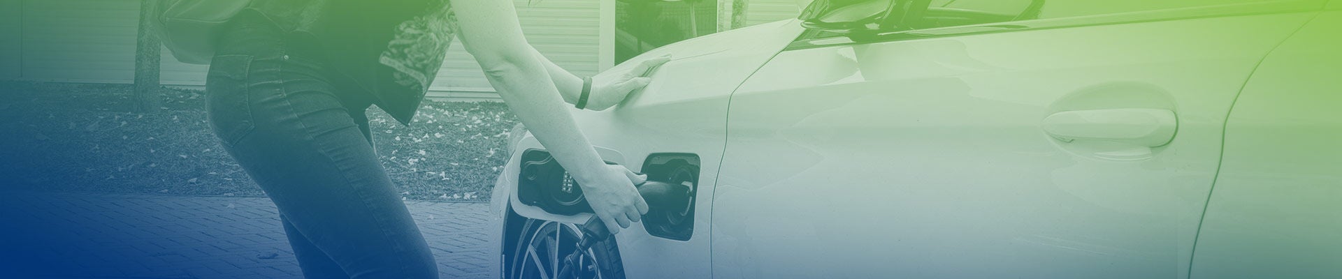 Une femme branche un véhicule électrique dans l’allée