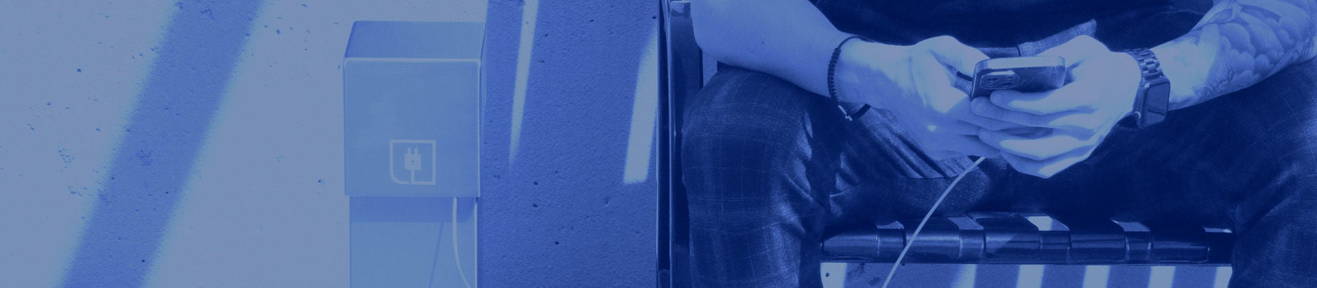 Un homme assis sur un banc charge un téléphone avec socle d’alimentation